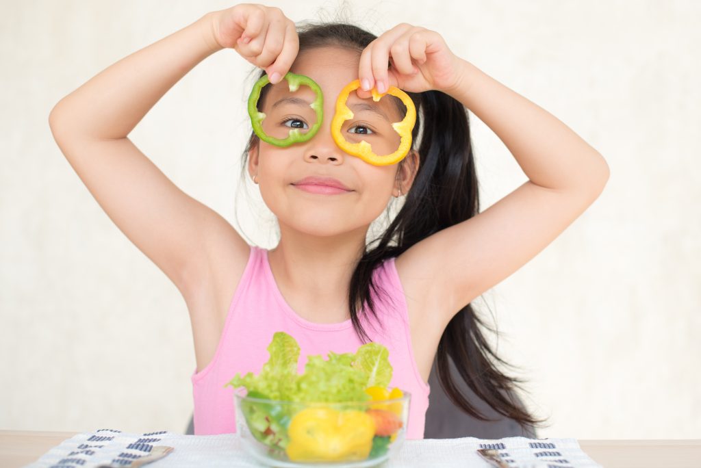 little asian girl enjoy eating with vegetable salad with bowl in breakfast time at home. eating vegetables by child make them healthier. kid girl having fun with food vegetables.Healthy food concept
